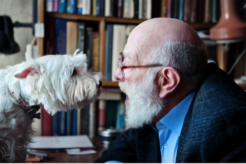 older man talking to his dog in his home office