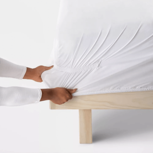 Close up of a woman putting Target's Threshold sheets on a bed