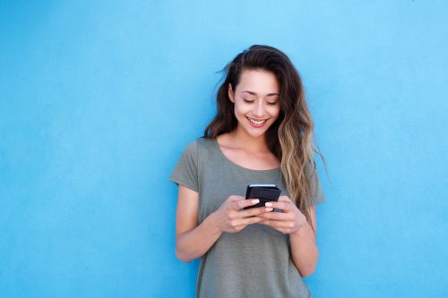 woman smiling while reviewing all the tinder pickup lines she has received on her phone