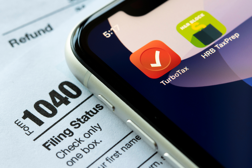 A TurboTax app logo on a phone screen resting on top of a 1040 tax form