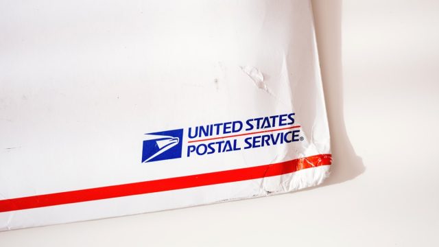 Close up view of damaged corner of USPS United States Postal Service Parcel envelope