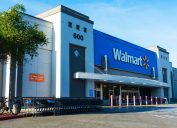 Walmart store facade. Row of shopping carts are ready for customers. Anti ram raiding bollards secure Wal-mart entrance from accident or theft