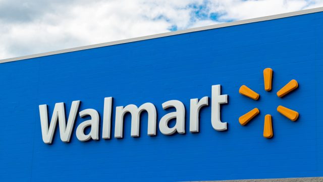 A Walmart sign in front of the store on a blue background