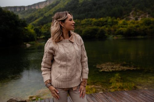Beautiful woman dressed beige sweater and trousers, walking in rainy weather at the forest against the background the lake