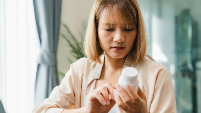 A woman looking at a medication bottle in her hand