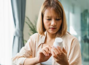 A woman looking at a medication bottle in her hand