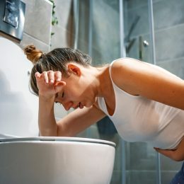 woman with norovirus getting sick in the bathroom over the toilet