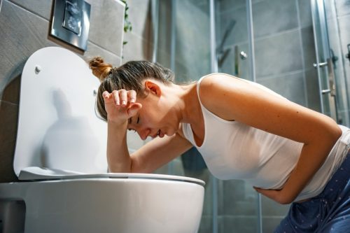 người phụ nữ nhiễm norovirus bị bệnh trong phòng tắm trên đỉnh nhà vệ sinh