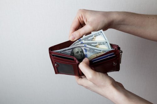 girl showing money in her wallet. lots of money in hand.