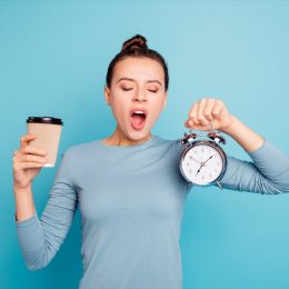 Tired Woman Holding Coffee and Clock
