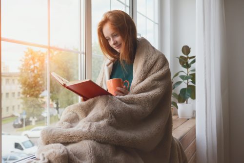 Woman Reading While Wrapped in a Blanket