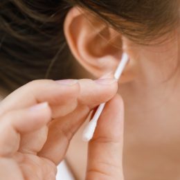 Woman is cleaning ear with a cotton swab
