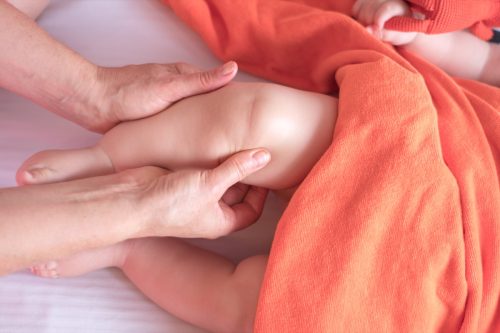woman massaging an infant's knee