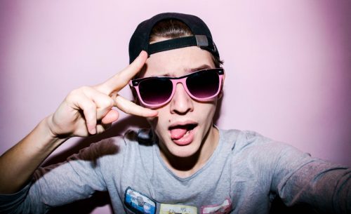 teen boy wearing sunglasses and making a peace sign for an Instagram selfie