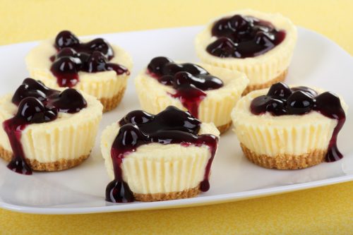 Plate of cheesecake cupcakes topped with blueberry sauce