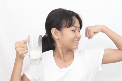 little girl drinking milk and showing off her muscles