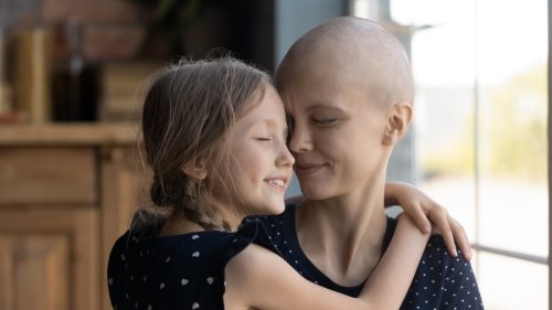 Happy young cancer patient sick mother and little daughter hug 