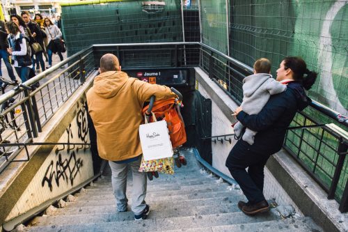man carrying a stroller down the subway stairs as a random act of kindness