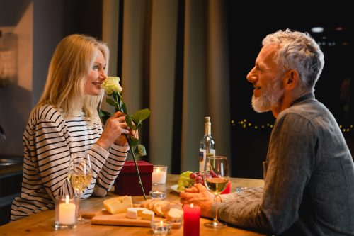 Một cặp vợ chồng hạnh phúc ở độ tuổi 50 đang hẹn hò ăn tối;  người phụ nữ ngửi thấy một bông hồng