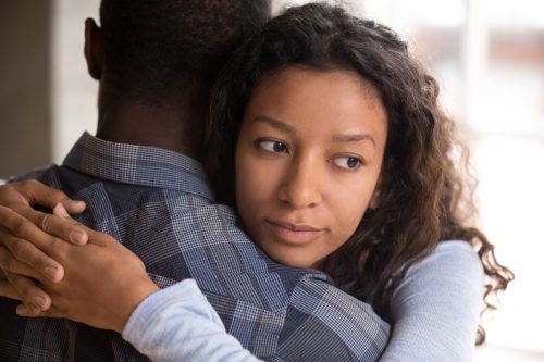 một cặp vợ chồng trẻ da đen ôm nhau, nhưng người phụ nữ có vẻ nghi ngờ