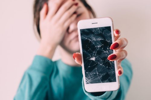 girl holding up a phone with a smashed screen