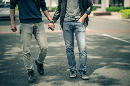 cropped photo of two men holding hands walking down the street