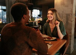 A young happy woman is in a restaurant on a Valentines date with her boyfriend.
