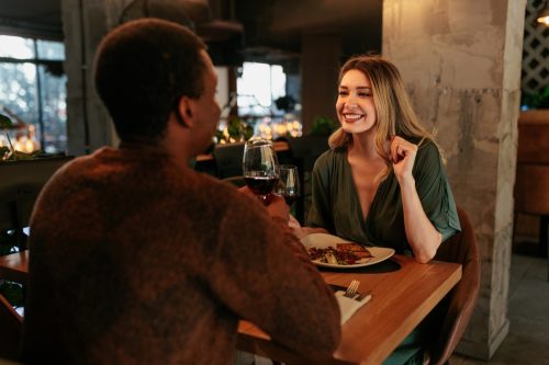 A young happy woman is in a restaurant on a Valentines date with her boyfriend.