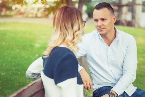 man and woman having a deep conversation on a park bench