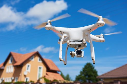 Close up of a drone in the sky with a house in the background