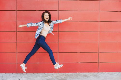 happy woman jumping against a a red wall