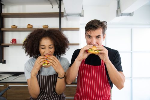young couple eating burgers side by side