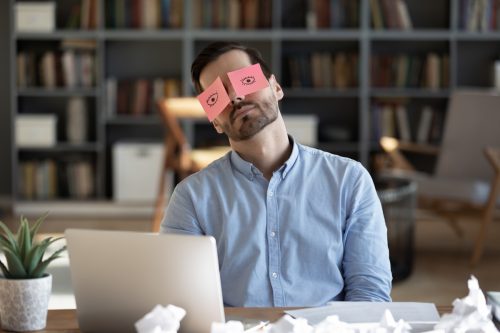 businessman on his computer with sticky notes over his eyes