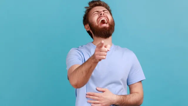 man laughing hysterically pointing at the camera