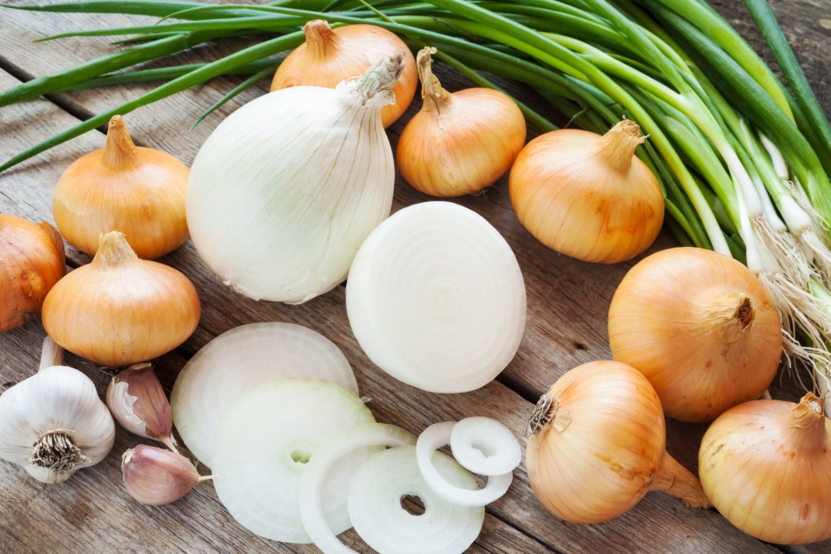 different onions and garlic bulb on wooden rustic table