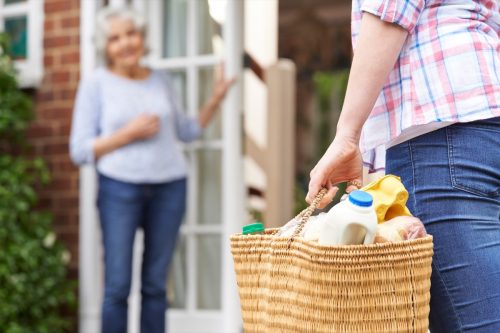 woman bringing groceries to her elderly neighbor as a random act of kindness