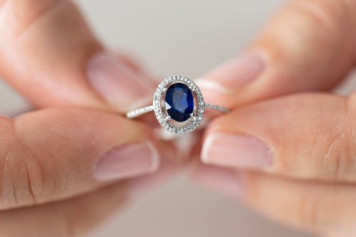 Close up of hands holding a sapphire and diamond ring