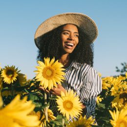 young happy black woman laughing in sunflower field