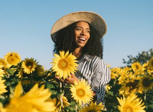 young happy black woman laughing in sunflower field