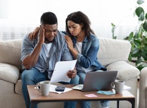 Family Financial Crisis Concept. Depressed Couple Looking At Invoice, Not Able To Pay Huge Bills