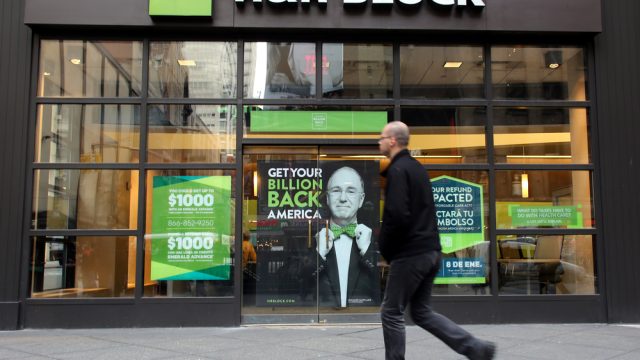 An H&R Block tax services storefront with a customer walking by