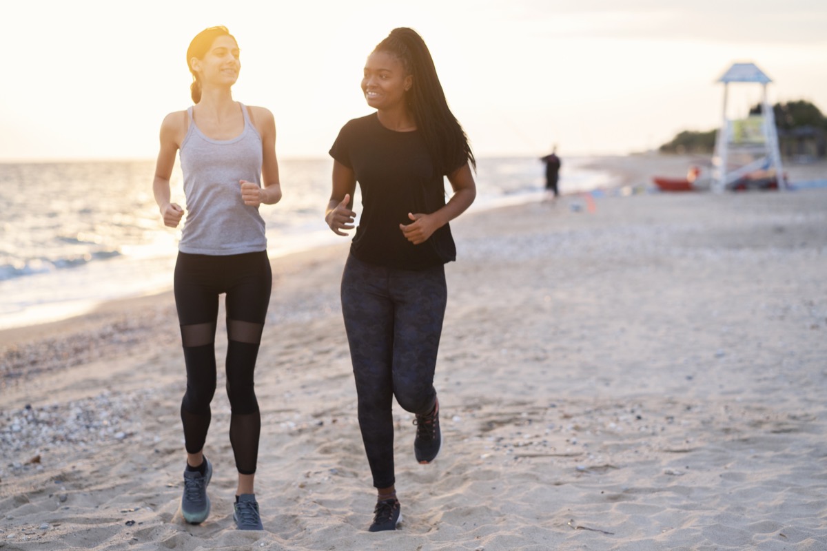 two friends running on the beach in leggings