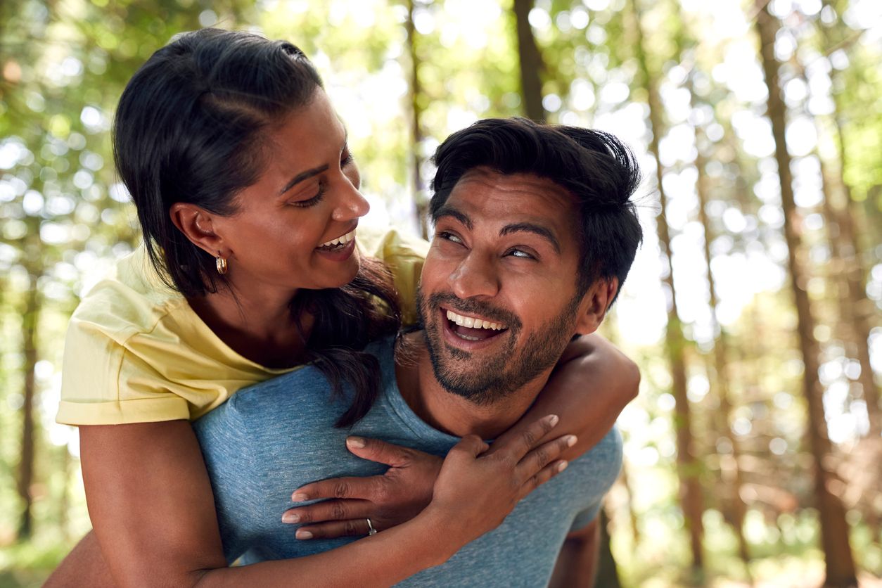 Man giving a woman a piggyback ride during a walk in the woods