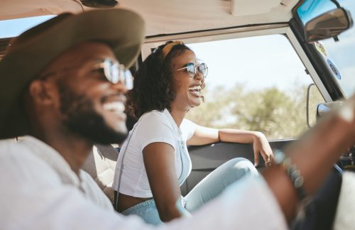 beautiful young black couple driving together in the summer, laughing in love