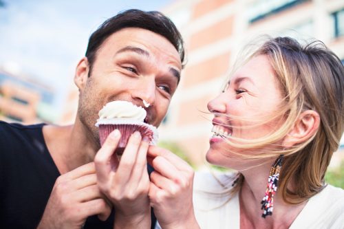 Joyful couple eating cupcake outdoors