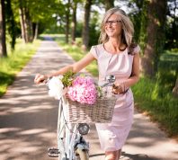 older woman wearing pink pastel dress with bike
