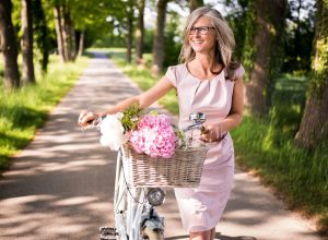 older woman wearing pink pastel dress with bike
