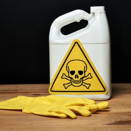 Container of toxic cleaning product and rubber gloves.