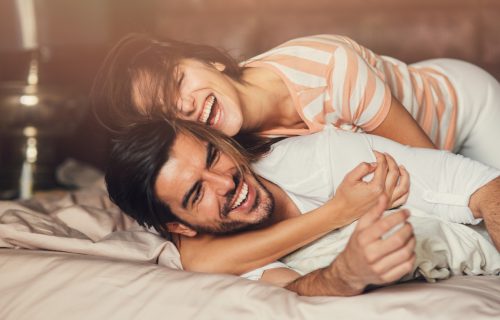 Happy young playful couple in bed.
