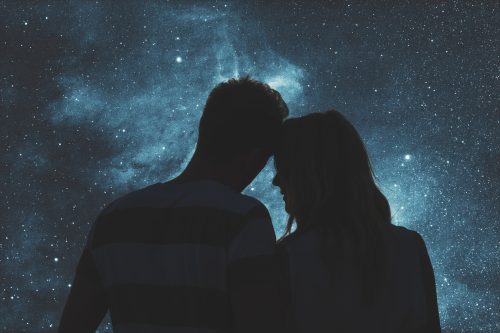 Silhouettes of a young couple under the starry sky